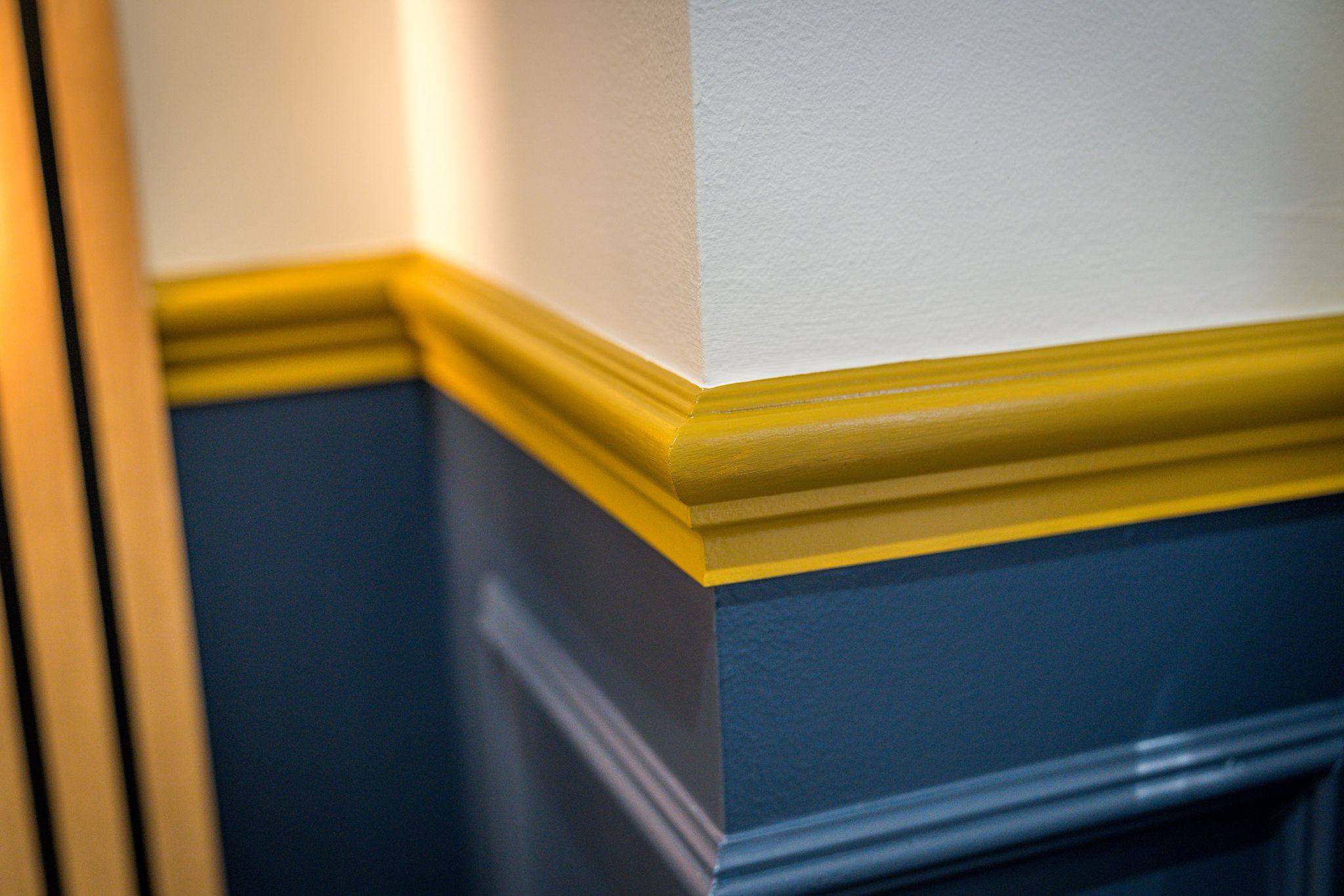 Hand-painted yellow dado rail detail against navy panelling